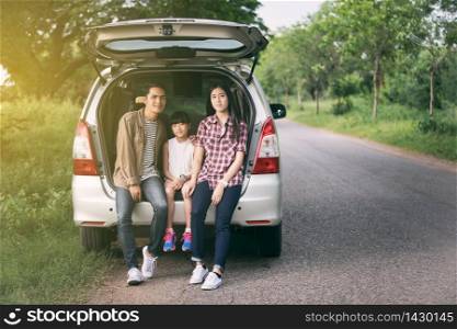 happy little girl with asian family sitting in the car for enjoying road trip and summer vacation