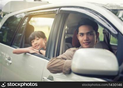happy little girl with asian family sitting in the car for enjoying road trip and summer vacation