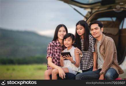 Happy little girl with asian family sitting in the car for enjoying road trip and summer vacation in camper van