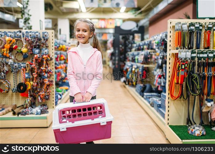 Happy little girl with pink carrier for cat in pet shop. Family buying accessories for kitten in petshop, cat-carrying