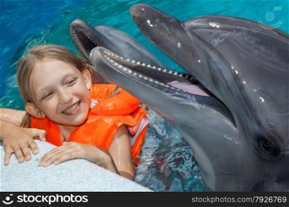 Happy Little Girl with two Dolphins in Swimming Pool