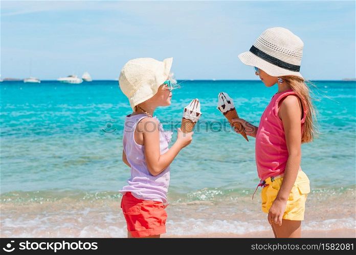 Happy little girls eating ice-cream on the beach at summer. Happy little girls eating ice-cream during beach vacation.