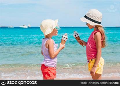 Happy little girls eating ice-cream on the beach at summer. Happy little girls eating ice-cream during beach vacation.