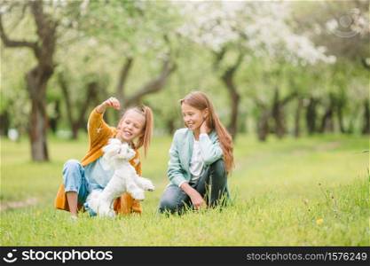 Happy little girls with a dog in the park. Little smiling girls playing and hugging puppy in the park