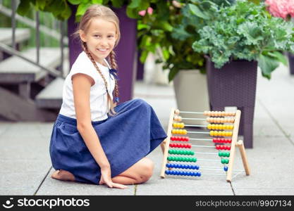 Happy little schoolgirl with accounts. Back to school outdoors. Happy little schoolgirl with a chalkboard outdoor
