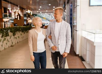Happy love couple at the jewellery shop. Male and female consumers buying jewels in jewelry store. Man and woman purchase gold decorations. Couple with shopping bags at the jewellery shop