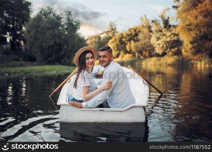 Happy love couple boating on lake at summer day. Romantic date, boat trip, man and woman walking along the river. Happy love couple boating on lake, romantic date