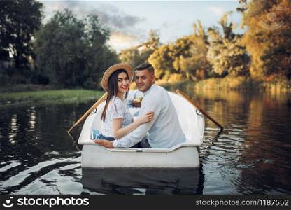 Happy love couple boating on lake at summer day. Romantic date, boat trip, man and woman walking along the river. Happy love couple boating on lake, romantic date