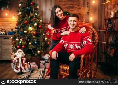 Happy love couple celebrate christmas holidays. Xmas celebration, cheerful man and woman together, fir-tree with decoration on background. Happy love couple celebrate christmas holidays