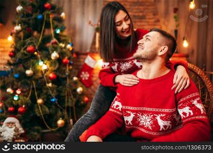 Happy love couple celebrate christmas holidays. Xmas celebration, cheerful man and woman together, fir-tree with decoration on background