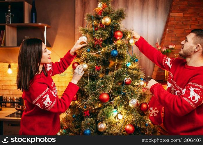Happy love couple decorate christmas tree. Xmas celebration, cheerful man and woman having fun together