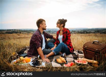 Happy love couple on picnic in summer field. Romantic junket of man and woman. Happy love couple on picnic in summer field