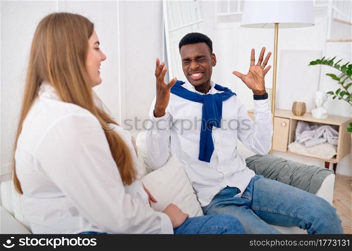 Happy love couple talking on sofa at home. Cheerful man and woman leisures on couch in their house. Husband and wife resting together. Happy love couple talking on sofa at home