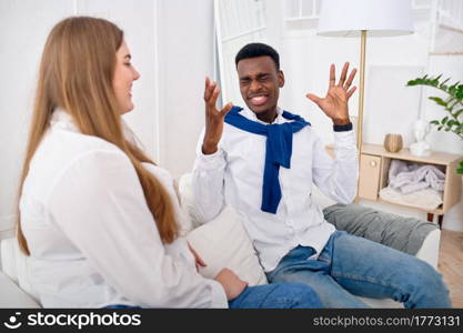 Happy love couple talking on sofa at home. Cheerful man and woman leisures on couch in their house. Husband and wife resting together. Happy love couple talking on sofa at home