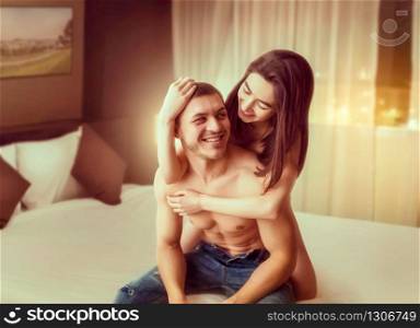 Happy love couple with naked body hugging on big white bed. Intimate games in bedroom, intimacy lovers. Happy love couple hugging on big white bed