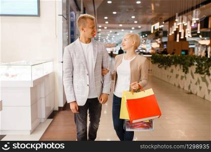 Happy love couple with shopping bags at the jewellery shop. Male and female consumers buying jewels in jewelry store. Man and woman purchase gold decorations