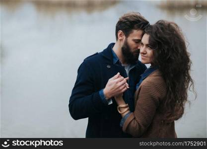 Happy lovers near the lake. Young couple is hugging on autumn day outdoors. A bearded man and curly woman in love. Valentine&rsquo;s Day. Concept of love and family. Happy lovers near the lake. Young couple is hugging on autumn day outdoors. A bearded man and curly woman in love. Valentine&rsquo;s Day. Concept of love and family.