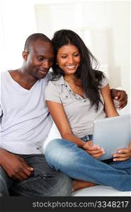 Happy loving couple sitting in sofa with electronic tablet
