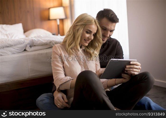 Happy loving couple sitting on the floor with digital tablet