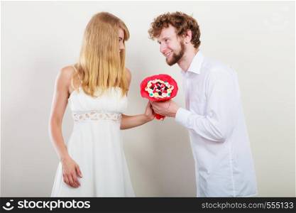 Happy loving couple with candy bunch bouquet flowers. Handsome man giving pretty woman present gift. Love concept.. Happy couple with candy bunch flowers. Love.