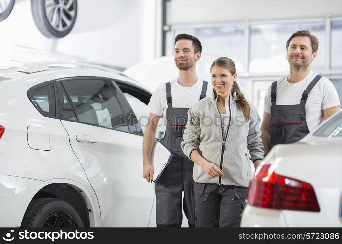 Happy maintenance engineers looking away in automobile repair shop