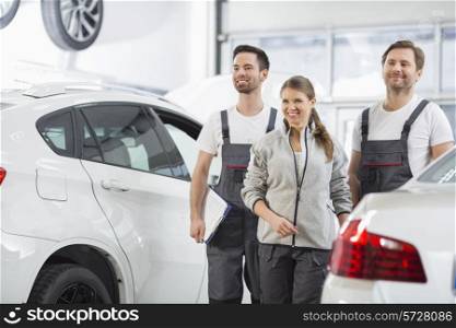 Happy maintenance engineers looking away in automobile repair shop