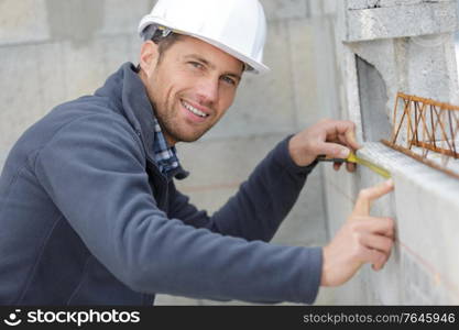 happy male builder with tape measure