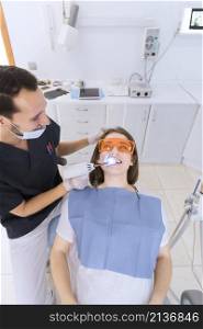happy male dentist checking patient s teeth with dental uv light equipment clinic
