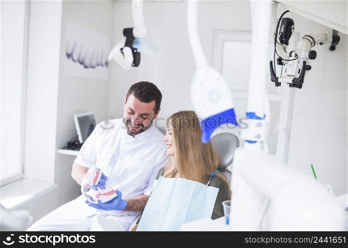 happy male dentist showing teeth model patient
