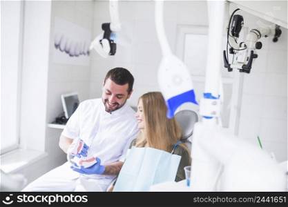 happy male dentist showing teeth model patient