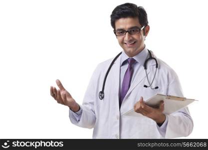 Happy male doctor holding clipboard while gesturing over white background