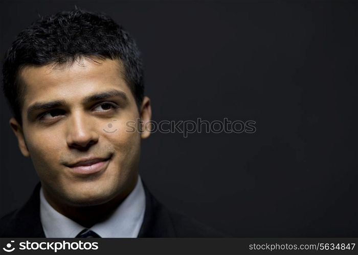 Happy male executive contemplating over black background