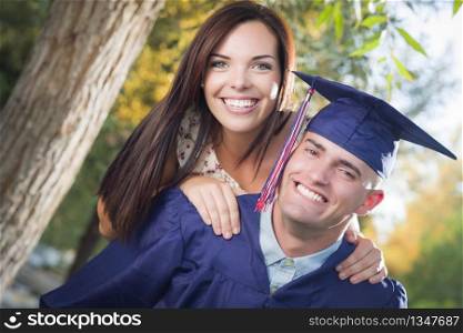Happy Male Graduate in Cap and Gown and Pretty Girl Celebrate Outside.