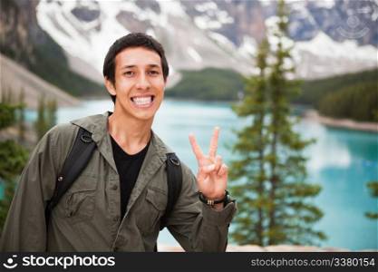 Happy male hiker showing you the victory sign against natural background