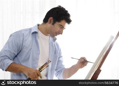 Happy male painter painting in art studio