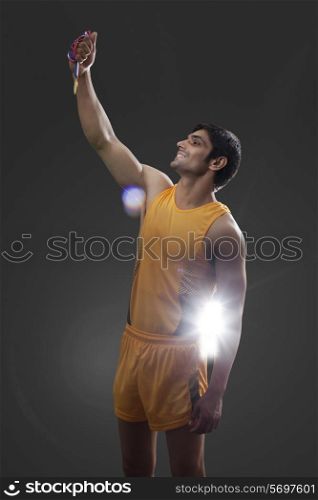 Happy male runner holding gold medal isolated over black background
