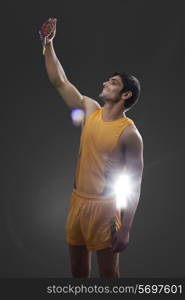 Happy male runner holding gold medal isolated over black background