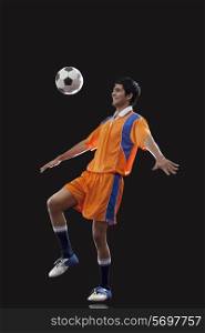 Happy male soccer player doing kick ups isolated over black background