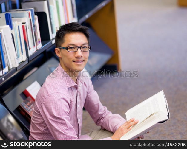 Happy male student holding books at the library. Happy male asian student holding books at the library