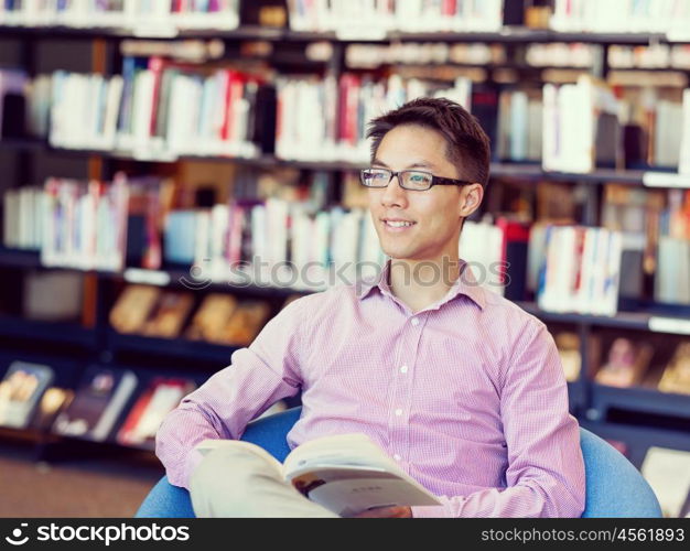 Happy male student holding books at the library. Happy male asian student holding books at the library