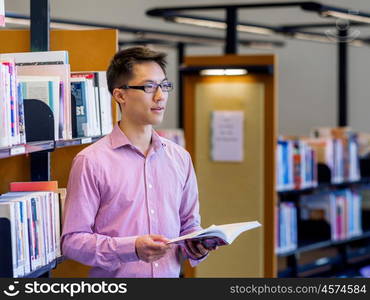 Happy male student holding books at the library. Happy male asian student holding books at the library