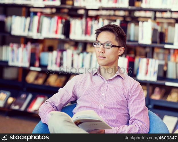 Happy male student holding books at the library. Happy male asian student holding books at the library