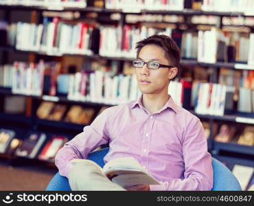 Happy male student holding books at the library. Happy male asian student holding books at the library