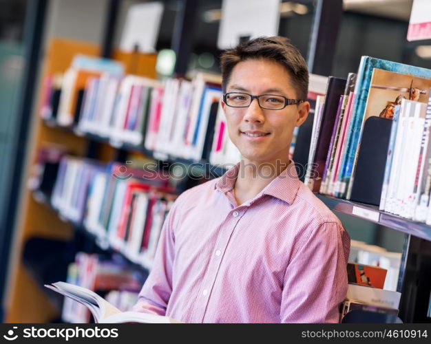 Happy male student holding books at the library. Happy male asian student holding books at the library