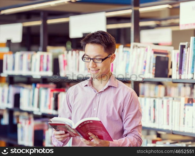 Happy male student holding books at the library. Happy male asian student holding books at the library