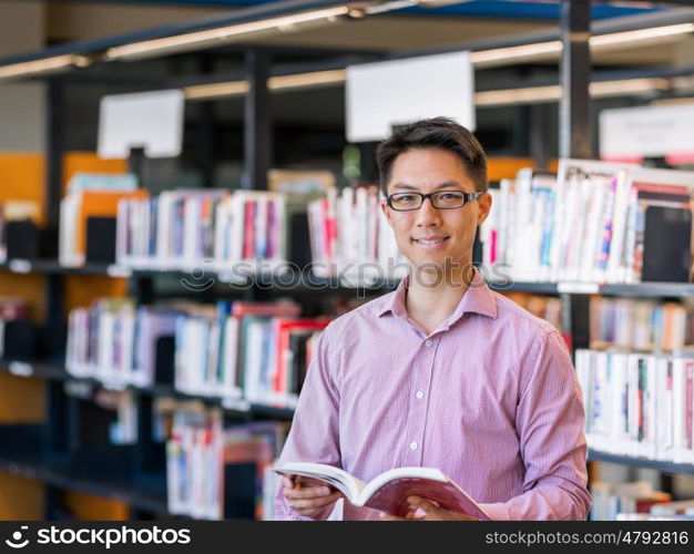 Happy male student holding books at the library. Happy male asian student holding books at the library