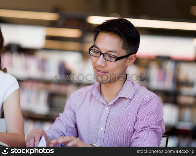 Happy male student holding books at the library. Happy male asian student holding books at the library