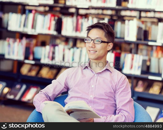 Happy male student holding books at the library. Happy male asian student holding books at the library