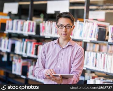 Happy male student holding books at the library. Happy male asian student holding books at the library