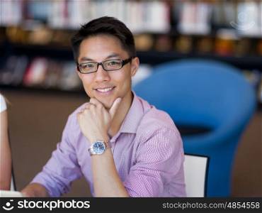 Happy male student working at the library. Happy male asian student working at the library